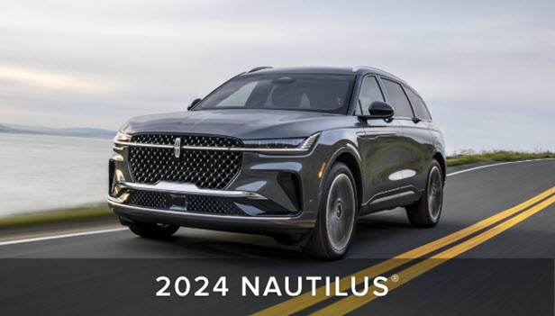 A 2022 Lincoln Nautilus in Flight Blue is parked on a docking area next to a scenic lake